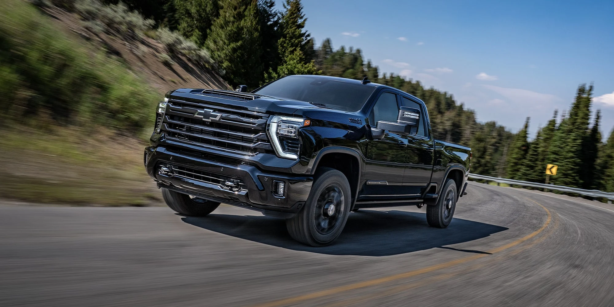 Black Chevrolet Silverado HD driving on a paved road