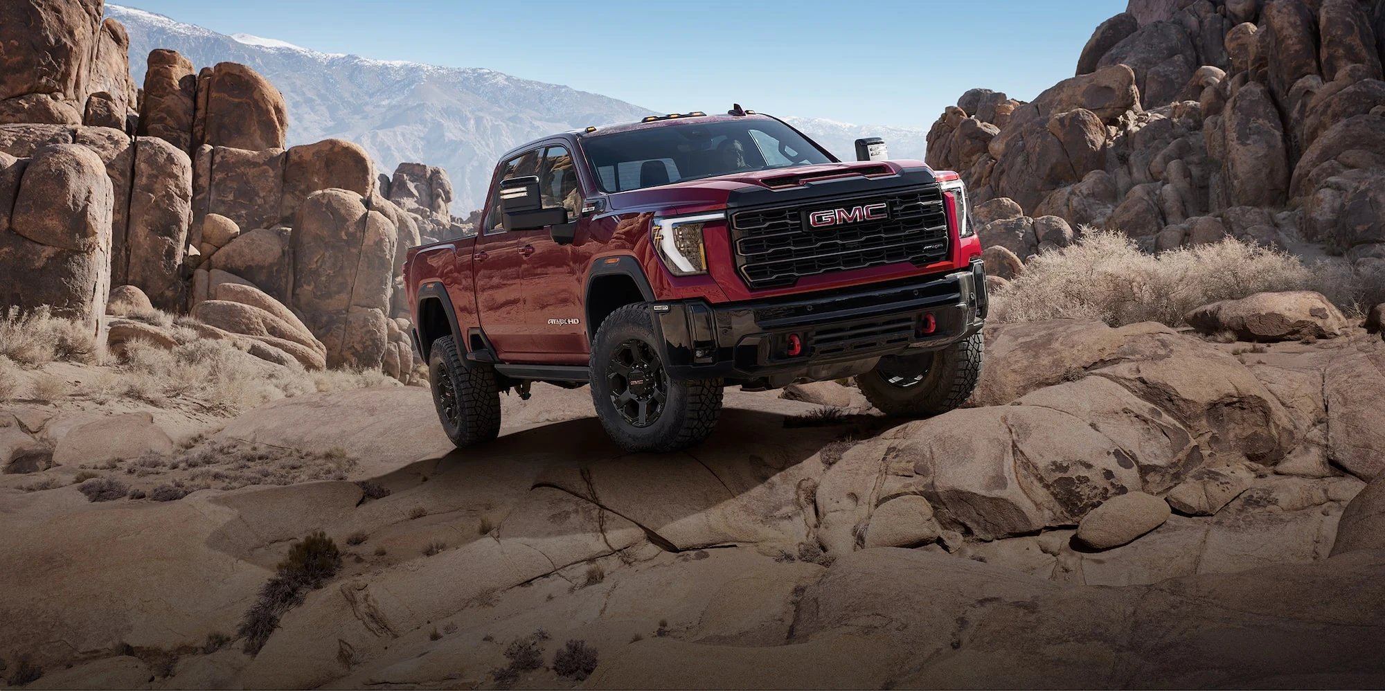 Red GMC Sierra HD AT4X crossing rocky terrain