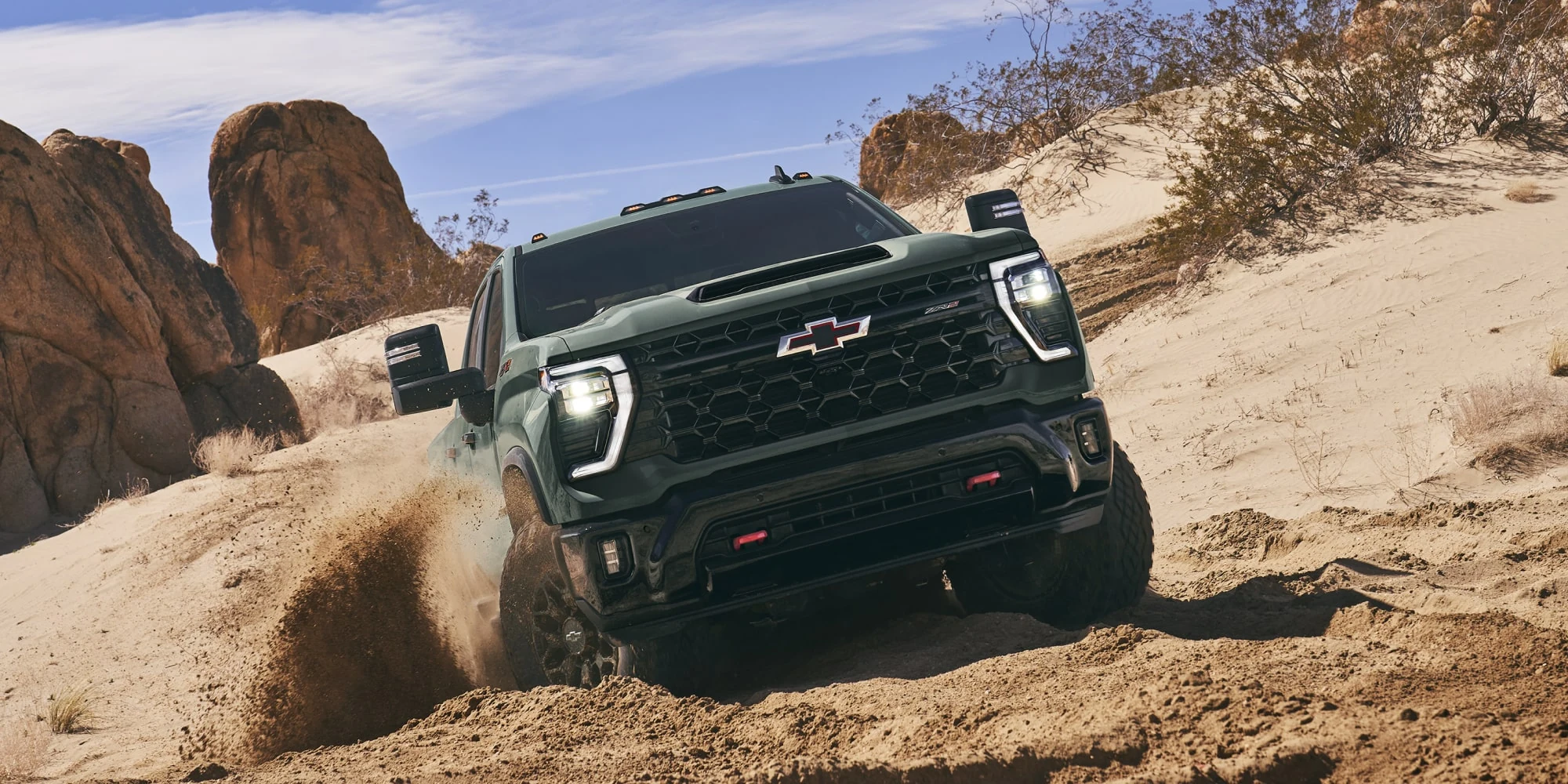 Dark Chevrolet Silverado HD driving off-road on sand