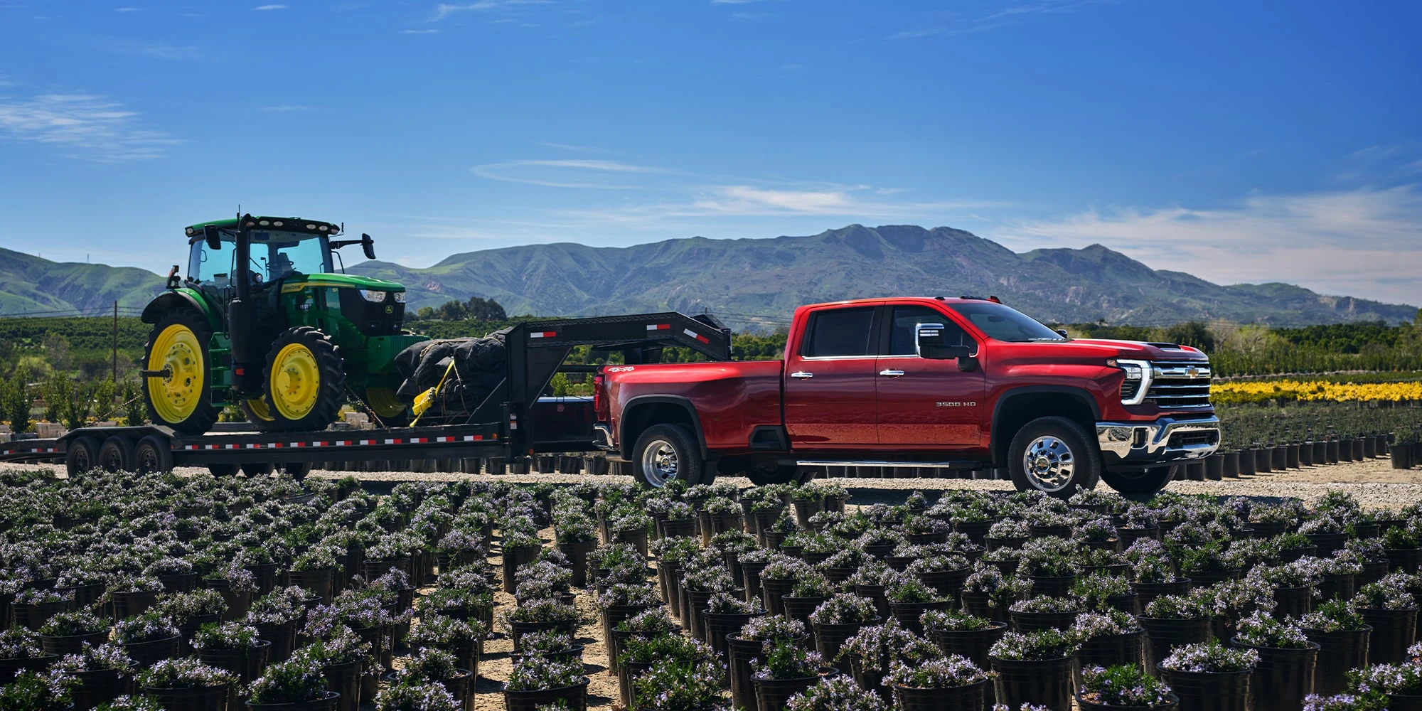 Red Chevrolet Silverado HD parked beside a tractor