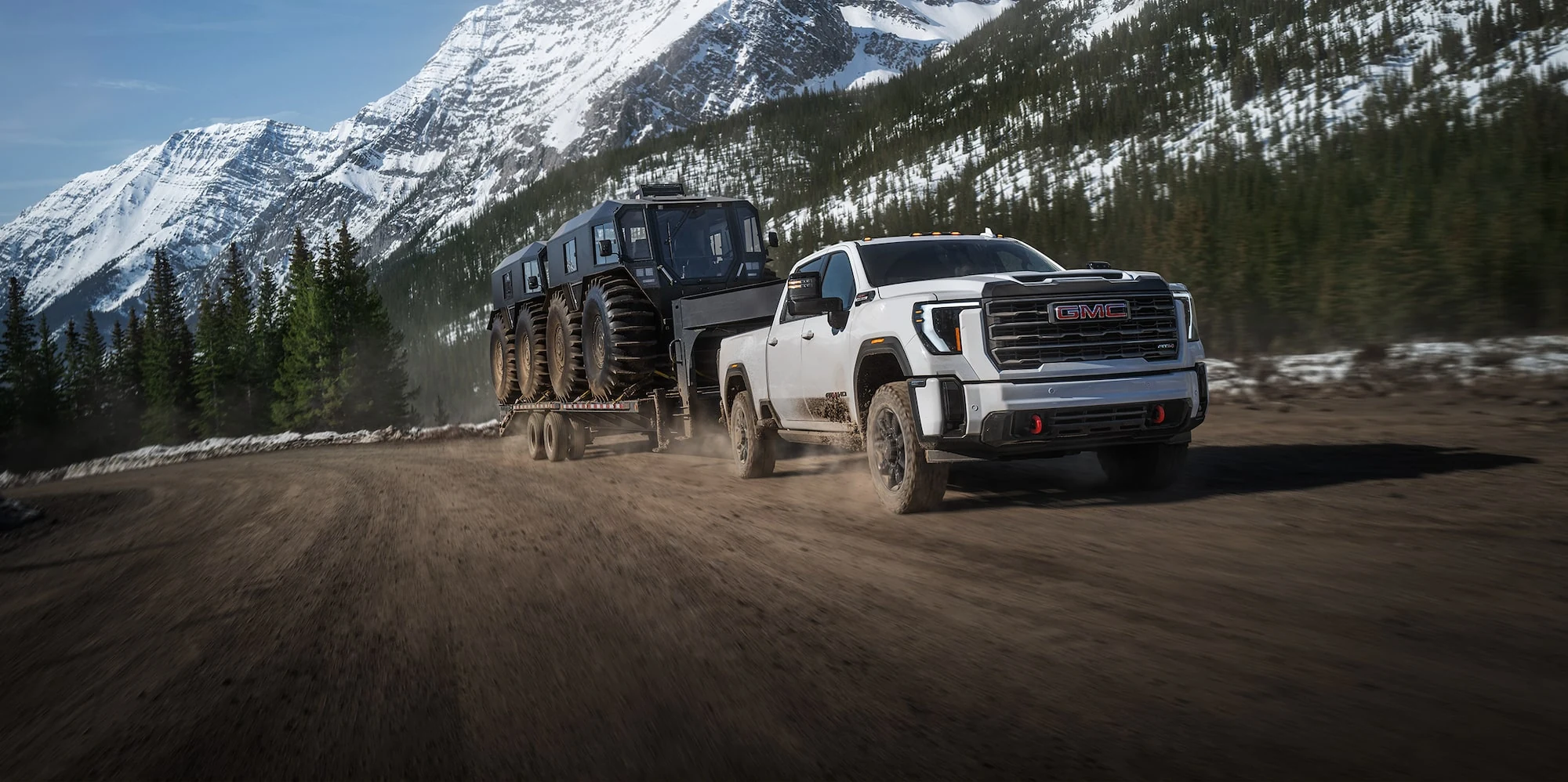 White GMC Sierra HD towing a large trailer on the road