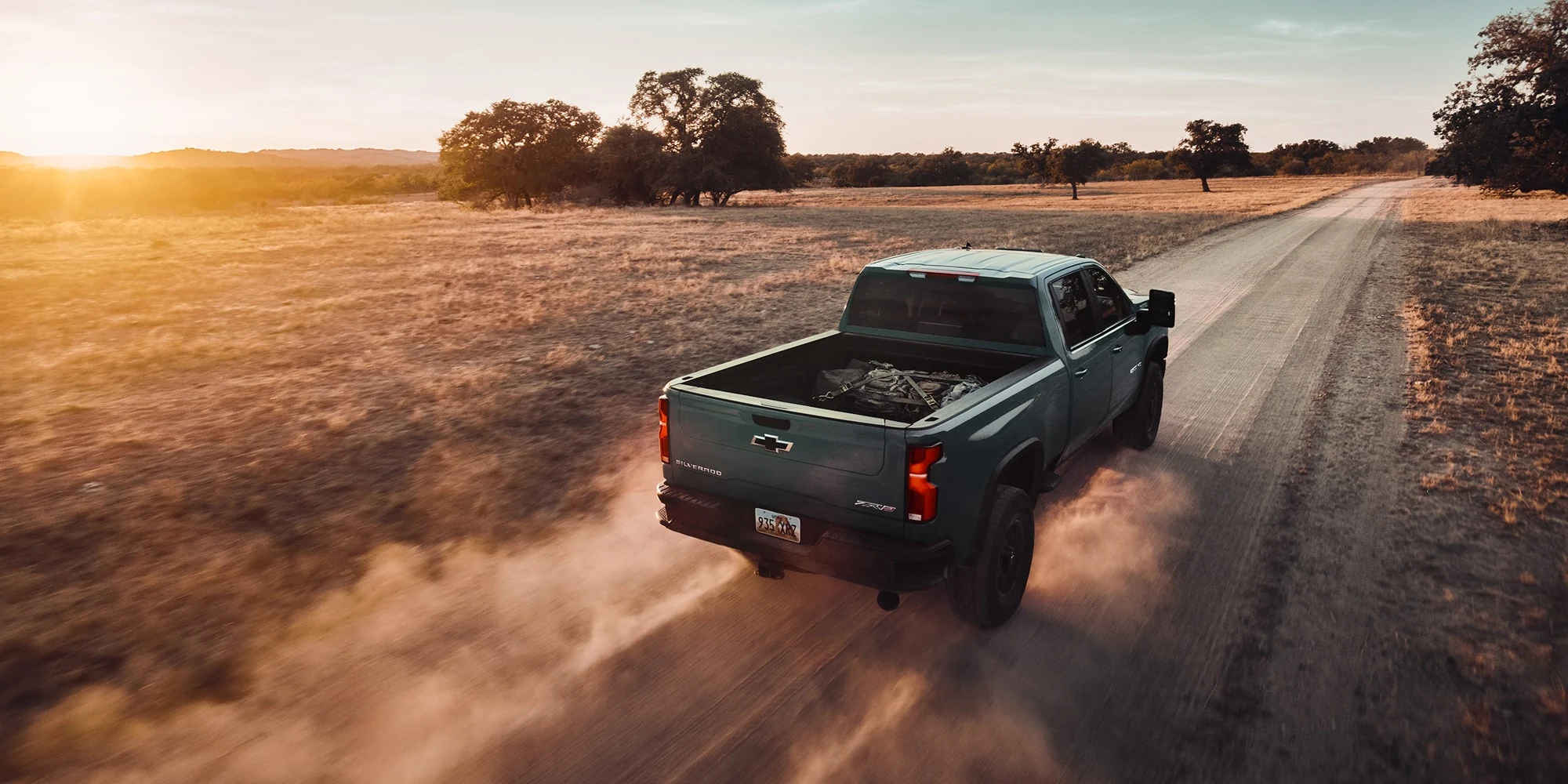 Green Chevrolet Silverado HD at sunset, rear three-quarter view