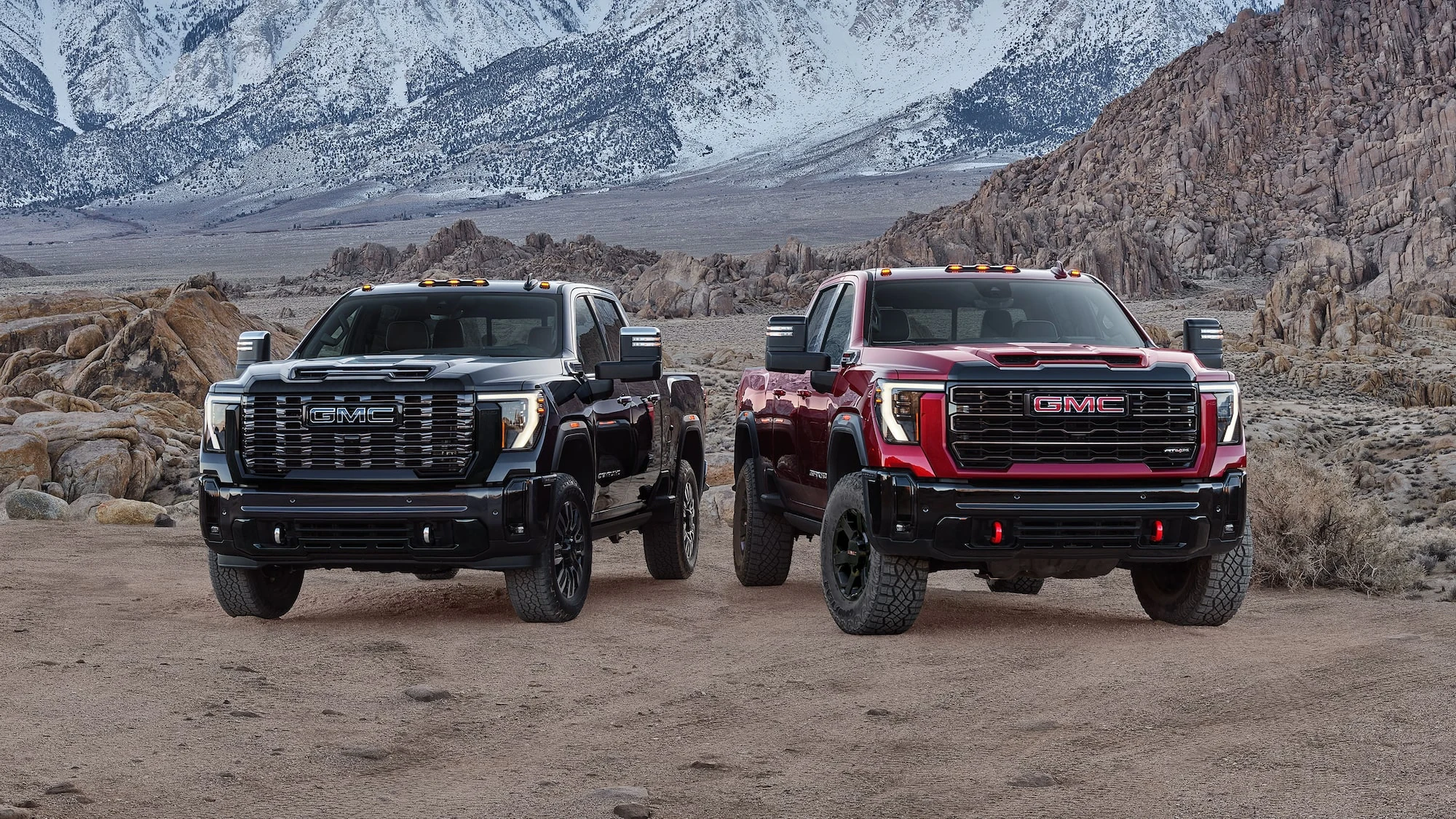 Black and red GMC Sierra HD pickups with mountains in the background